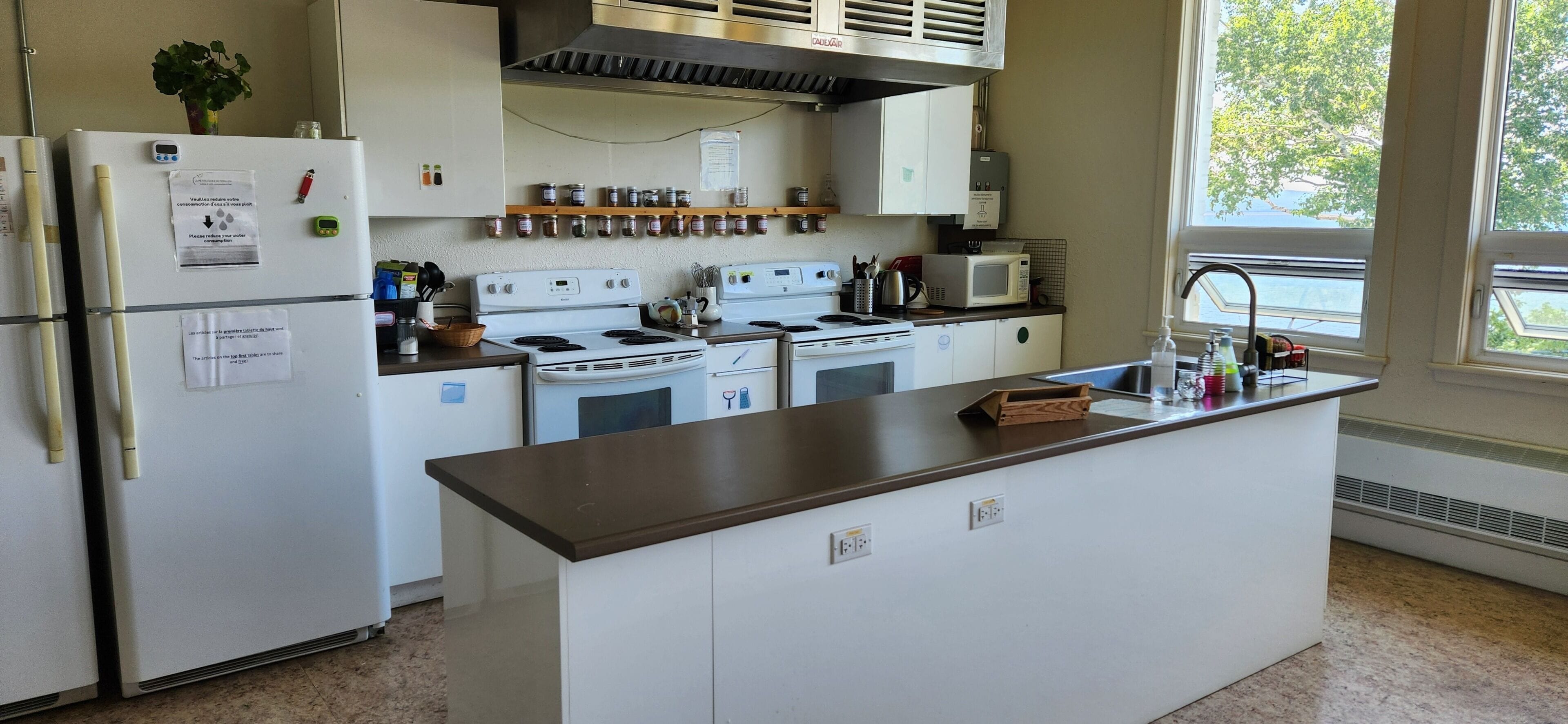 Una cocina con electrodomésticos blancos, una isla central y un ventanal que proporciona luz natural.