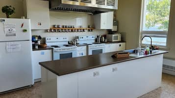 Una cocina con electrodomésticos blancos, una isla central y un ventanal que proporciona luz natural.