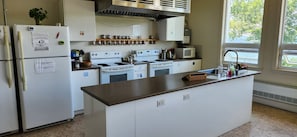 Una cocina con electrodomésticos blancos, una isla central y un ventanal que proporciona luz natural.