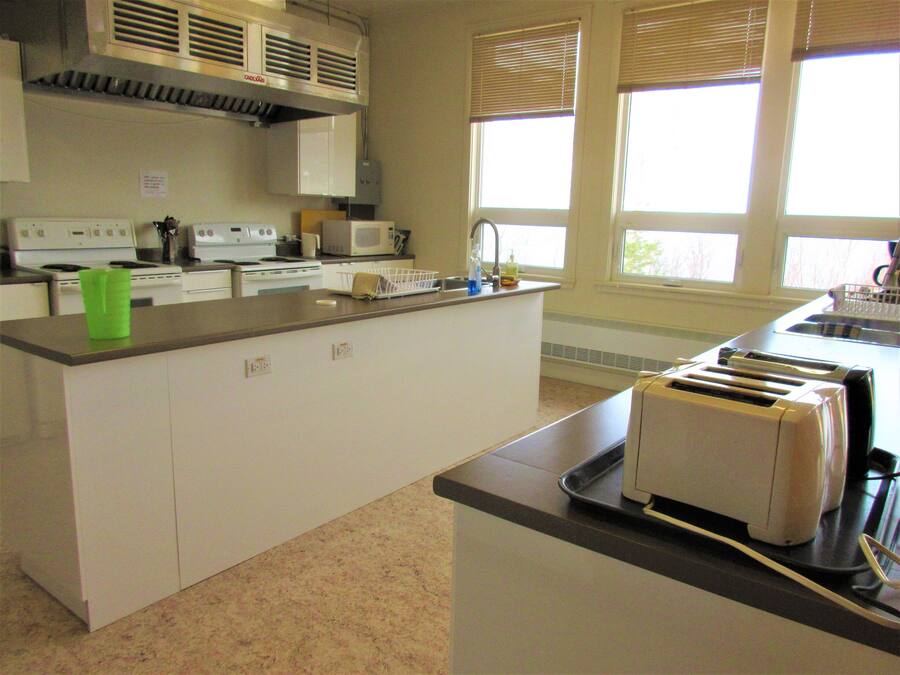 A kitchen with white cabinets, a microwave, a toaster, and a window with blinds.