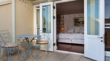 Un patio abierto con una cama, dos sillas y una mesa.