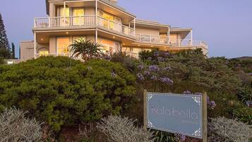 A multi-story coastal house with a sign reading "Isola Bella Guest House".