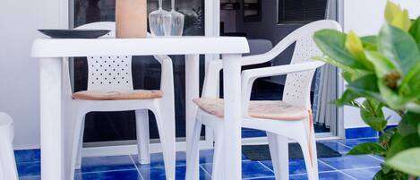A white table with two chairs, a vase with flowers, and a number sign above the door.