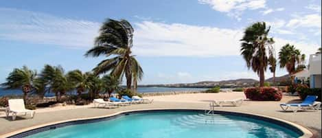 Una piscina al aire libre, sombrillas, sillones reclinables de piscina