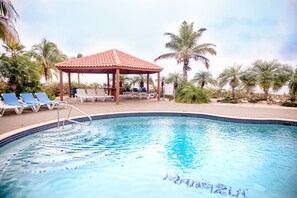Une piscine avec des chaises longues et un kiosque.