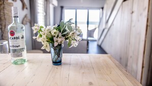 Een fles Bacardi Superior rum en een vaas met witte bloemen op een houten tafel in een modern interieur.
