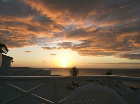 Un atardecer sobre el océano, con vista al mar y un edificio en primer plano.