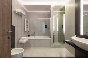 A modern bathroom with a bathtub, shower, and sink.