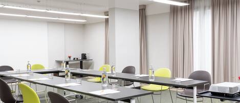 A conference room with a long table, chairs, a projector, and a water dispenser.