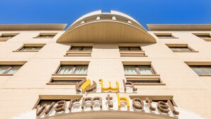 Un hôtel reconnaissable à son grand panneau « Warmhotel », à ses nombreuses fenêtres et à sa façade symétrique.