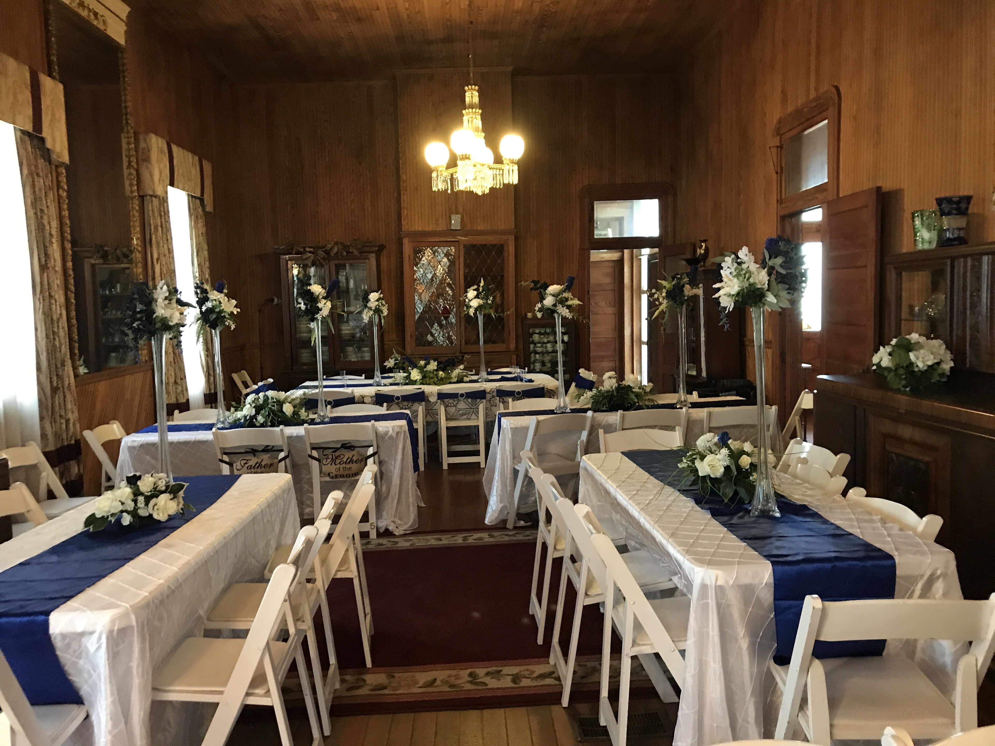 A banquet hall with round tables, white chairs, and blue tablecloths.