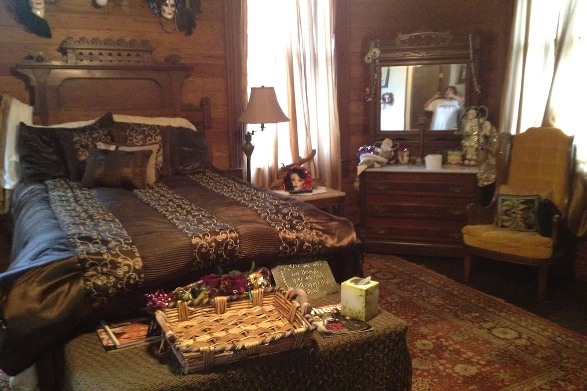 Una habitación tradicional con una cama grande, un aparador, un espejo y una mesita con una cesta.