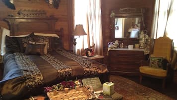 Quarto tradicional com uma cama grande, cômoda, espelho e uma pequena mesa com um cesto.