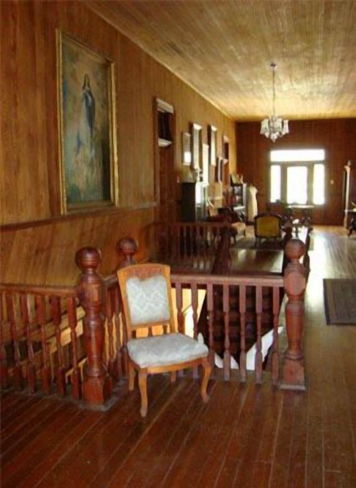 Une pièce au plancher de bois, avec une table à manger, des chaises et un lustre.