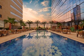 A hotel pool area with a tiled pool, palm trees, and outdoor seating. - Makkah Al Aziziah (Makkah)