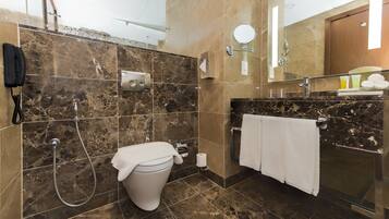 Ein modernes Badezimmer mit einer Marmerdusche, einer Toilette, einem Waschbecken mit Handtuchhalter und einem Spiegel.