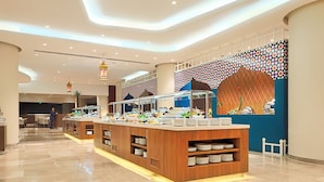 Um hall de hotel moderno com área de buffet, balcão de recepção e parede estampada.