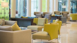 Um lobby moderno com várias áreas de estar, incluindo sofás e poltronas, dispostas em um espaço amplo.