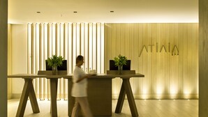 A reception area with a wooden reception desk, two potted plants, and a wall with vertical wooden slats. - Grand Hyatt Rio De Janeiro (Rio de Janeiro)