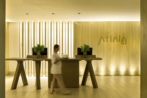 A reception area with a wooden reception desk, two potted plants, and a wall with vertical wooden slats. - Grand Hyatt Rio De Janeiro (Rio de Janeiro)