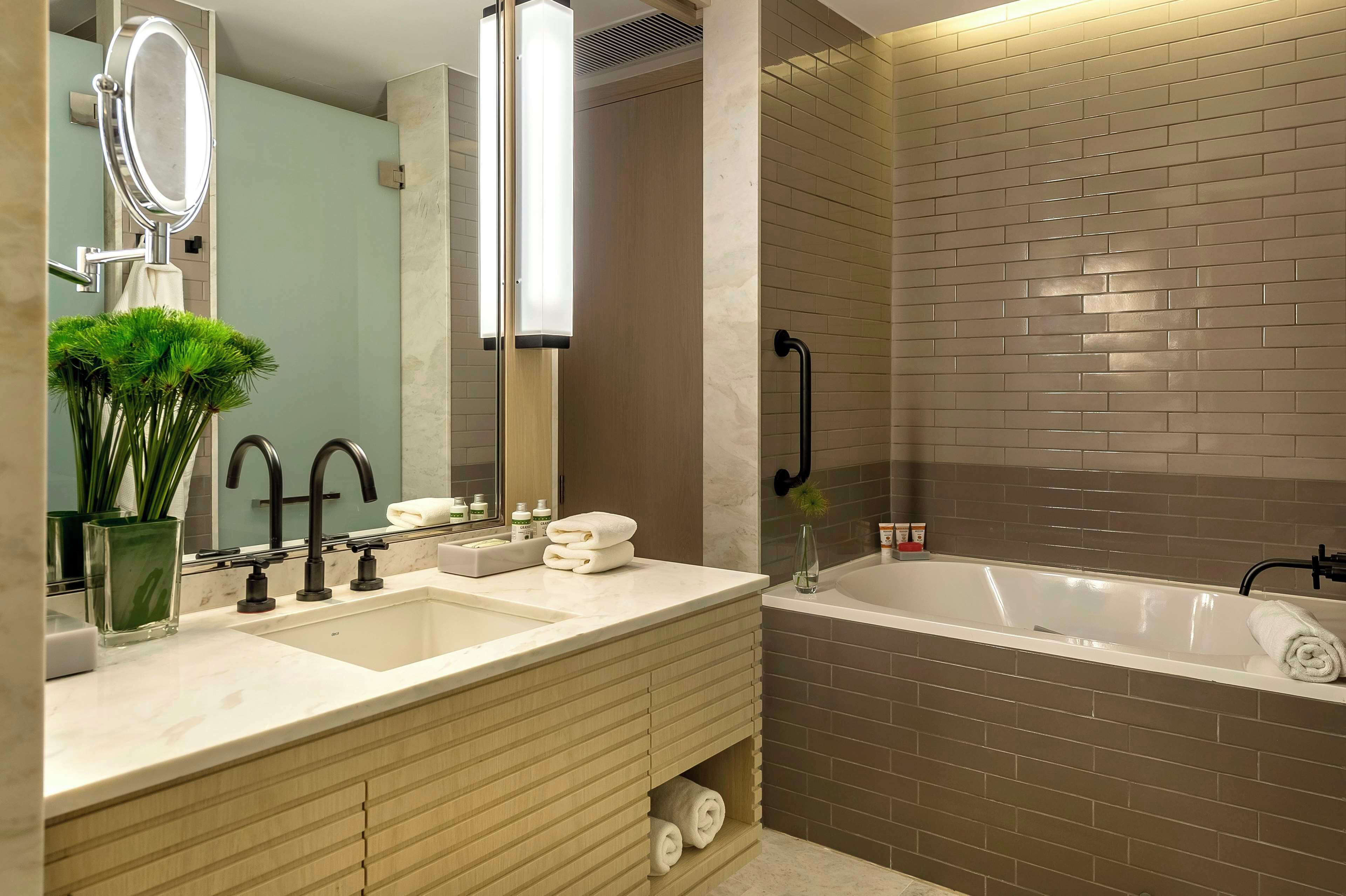 Un baño moderno con un espejo grande, dos lavamanos, una bañera y una zona de ducha.