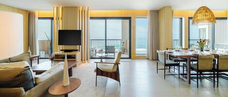 Amplia sala de estar con sofá, televisión, mesa de comedor para cuatro personas y balcón con vistas.