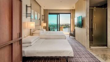 Quarto de hotel com duas camas, televisão, varanda com vista e área de duche.