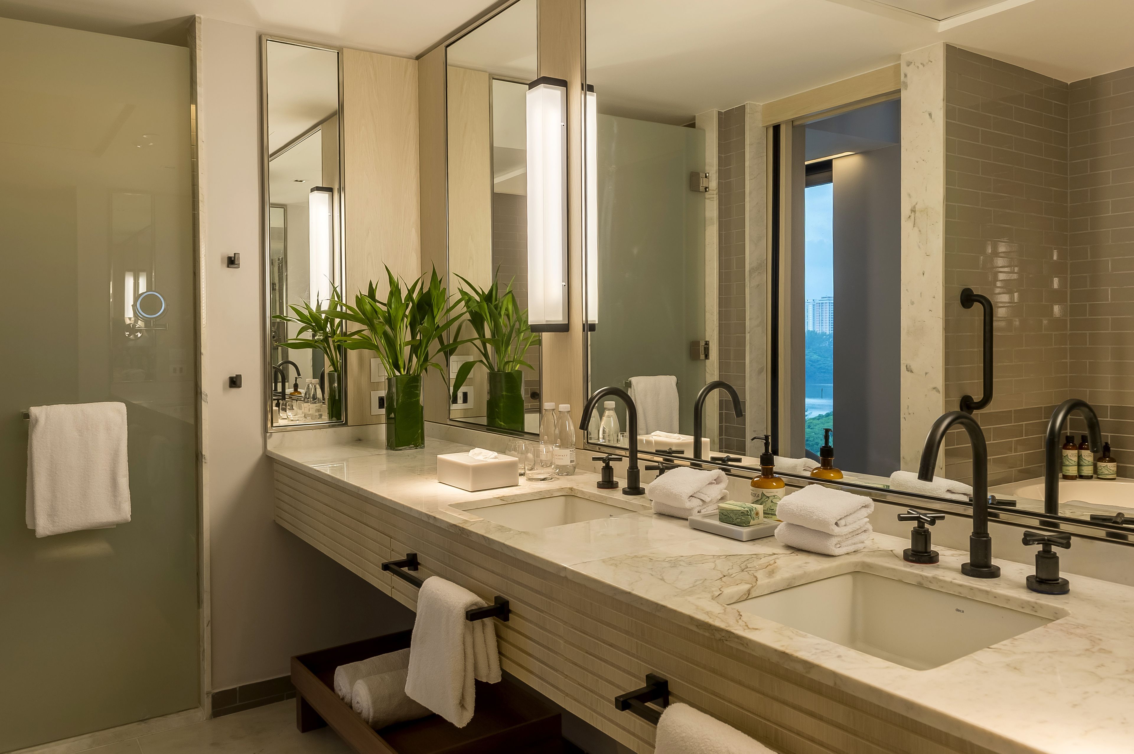 Un baño moderno con un espejo grande, dos lavamanos y una zona de ducha.
