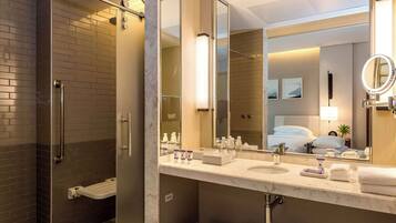 Uma casa de banho moderna com cabine de duche em vidro, um espelho grande e toucador com artigos de higiene pessoal.