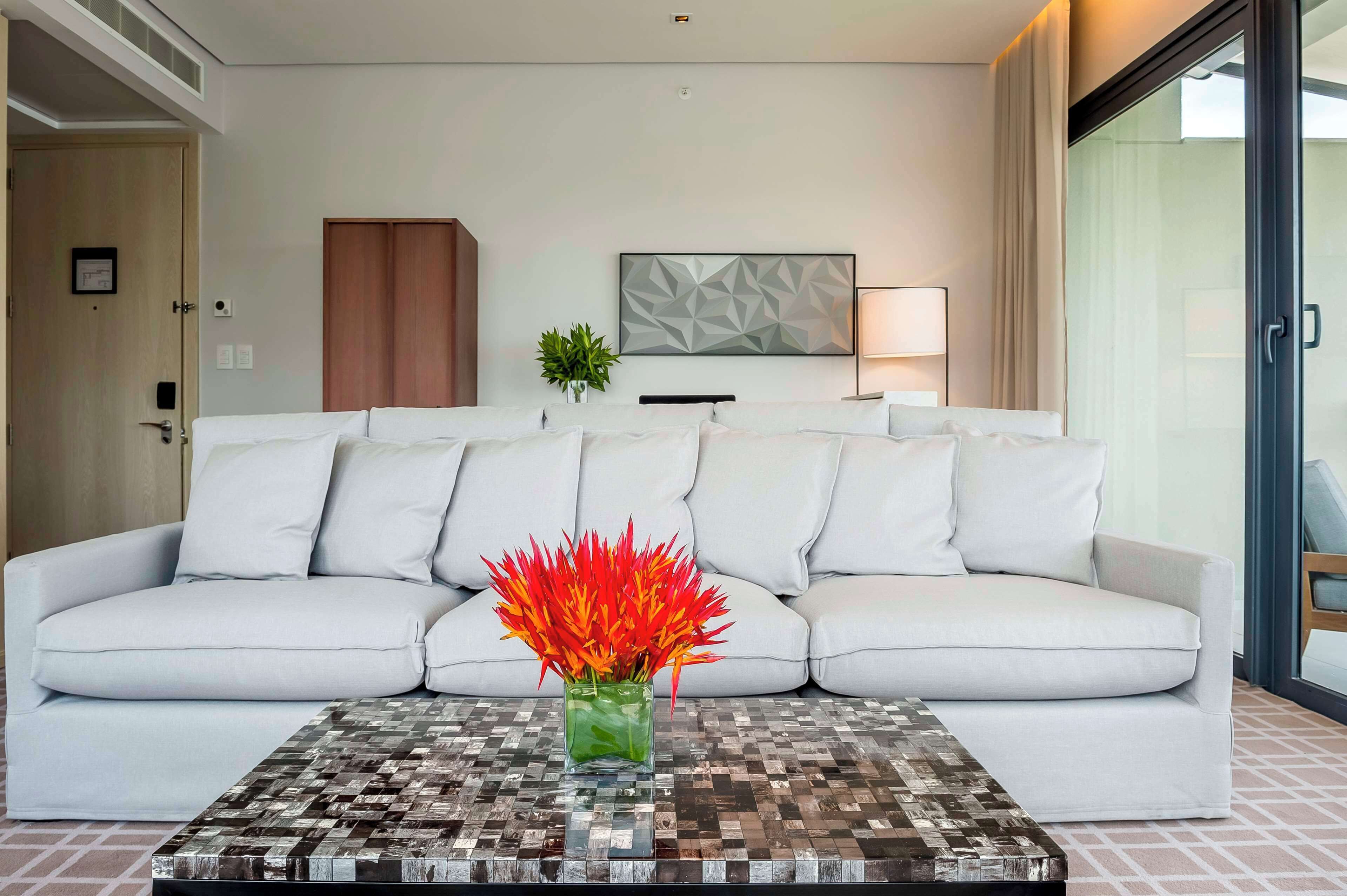 A modern living room with a white sofa, a patterned coffee table, and a geometric wall art piece.