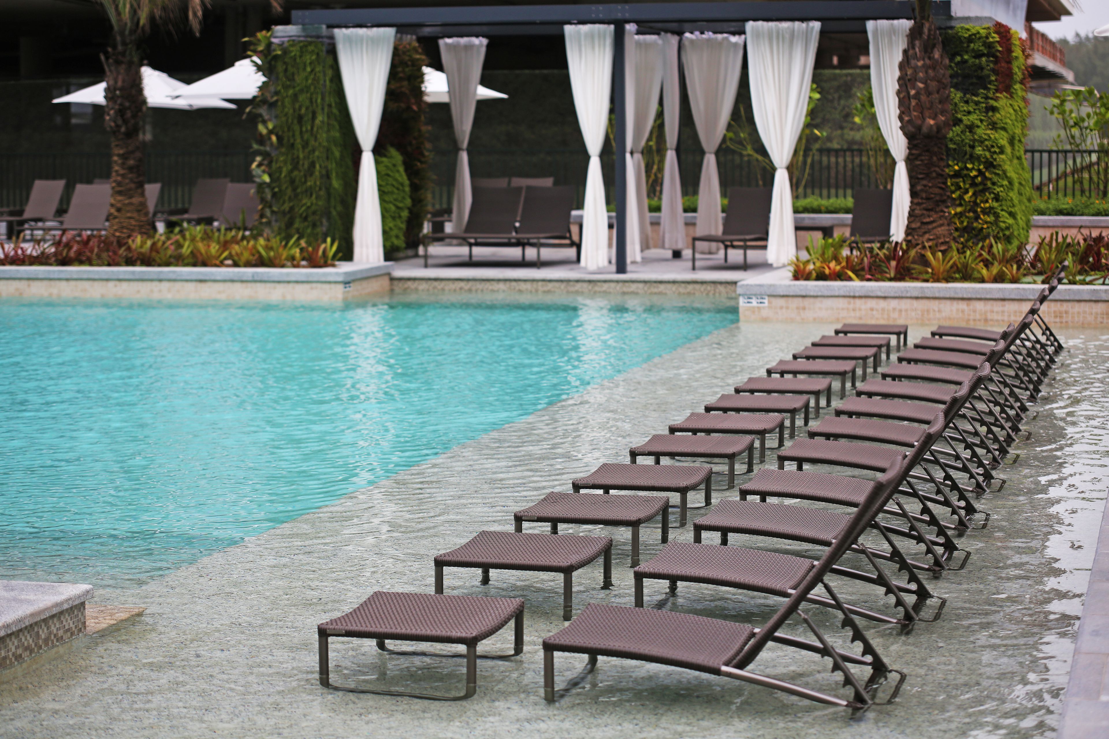 Un área junto a la piscina con sillones de descanso y una zona de estar techada.