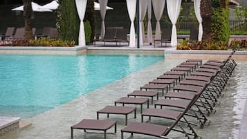 Un área junto a la piscina con sillones de descanso y una zona de estar techada.