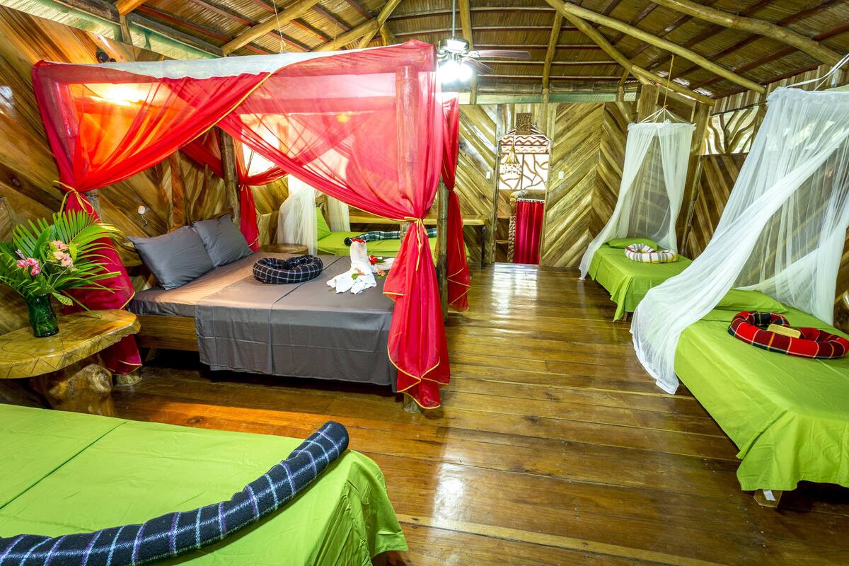 Una habitación con dos camas, cada una con dosel y cubrecama verde.