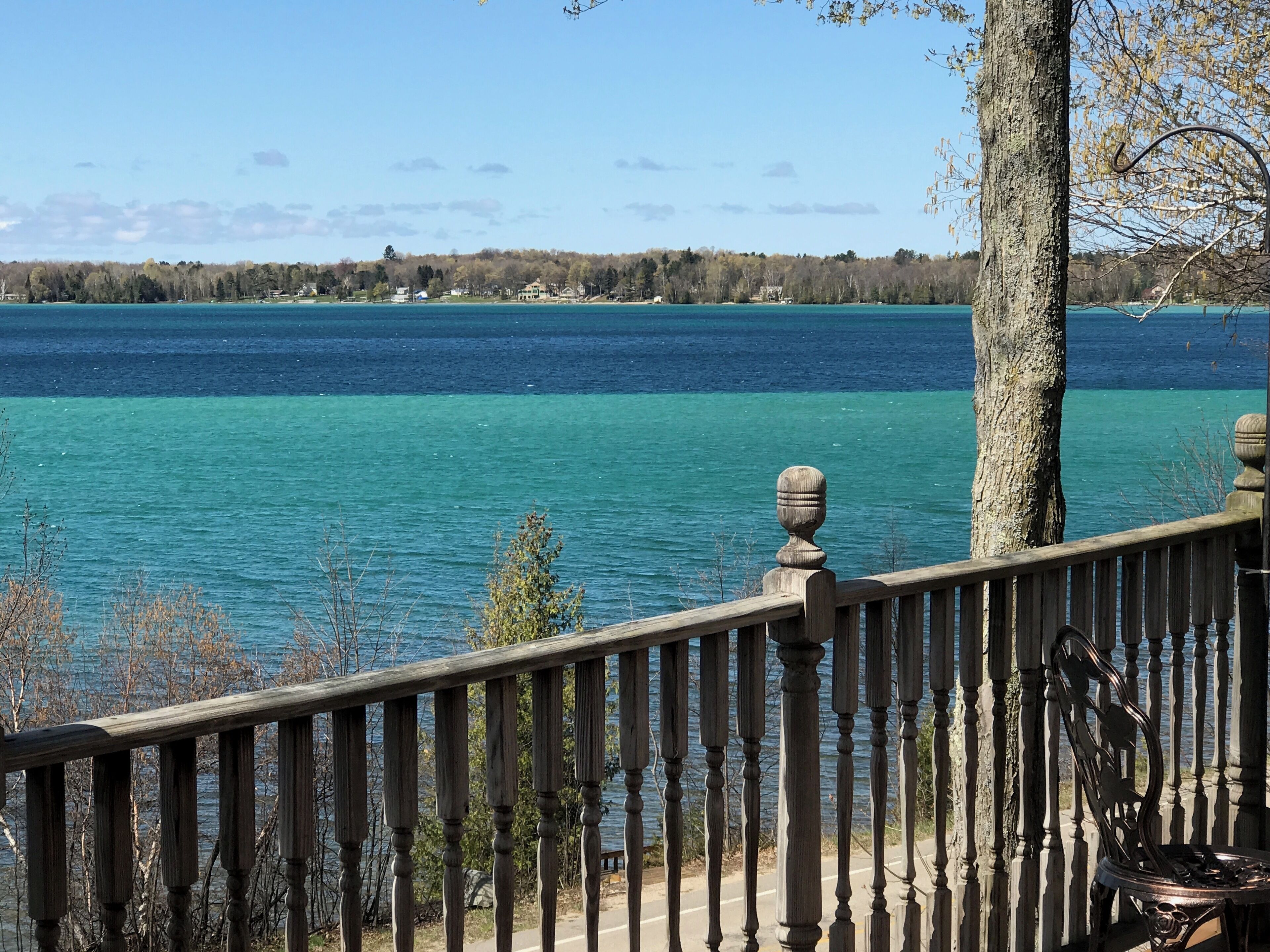 A wooden deck with a railing overlooking a lake.
