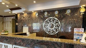 A reception desk with a marble countertop, a decorative wall piece, and clocks. - Hotel Buyuk Hamit (Istanbul)