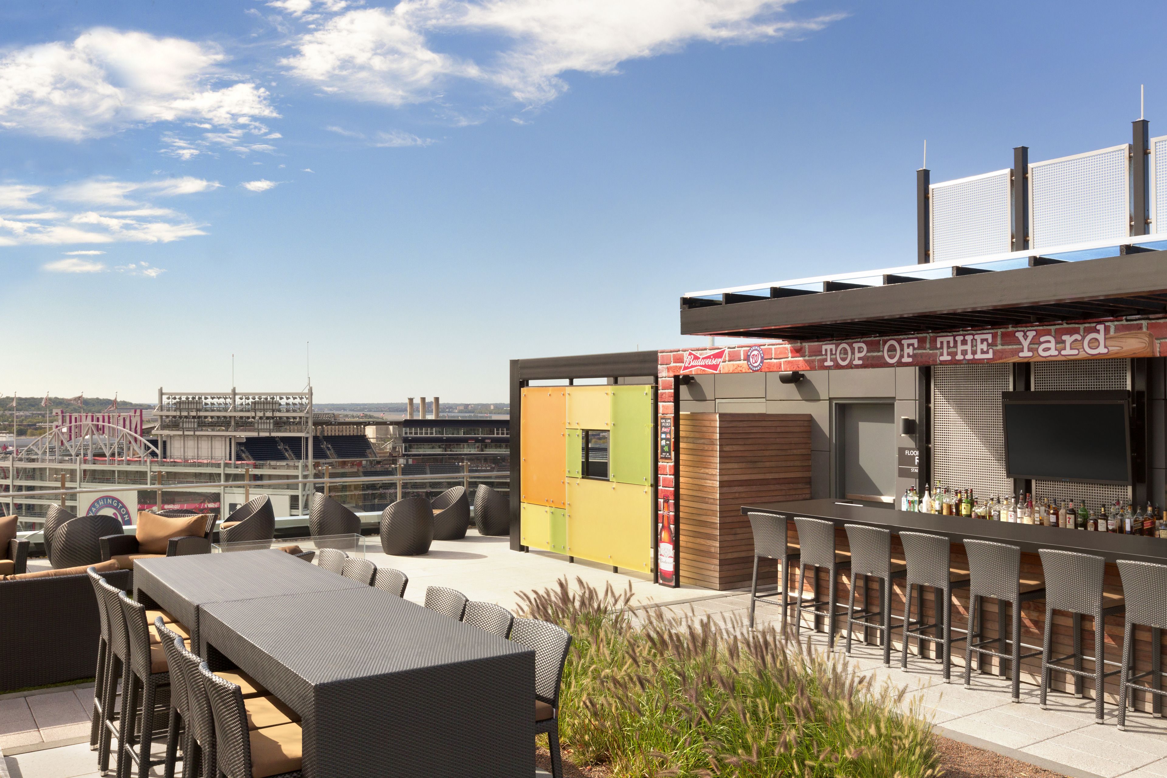 An outdoor bar area with seating and a view of a stadium.