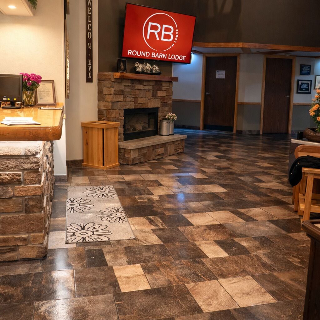 En lobby med en stenspir, et fjernsyn der viser 'Round Barn Lodge' og en receptionsdisk.