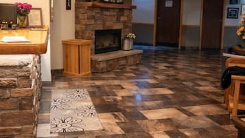 En lobby med en stenspir, et fjernsyn der viser 'Round Barn Lodge' og en receptionsdisk.