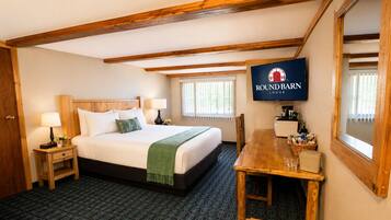 A hotel room with a bed, bedside tables, a TV, a wooden dining table, and a window.