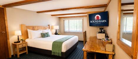 A hotel room with a bed, bedside tables, a TV, a wooden dining table, and a window.