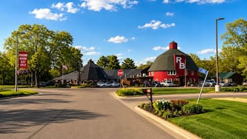 Un bâtiment rouge avec un toit particulier, un panneau de signalisation indiquant un arrêt et un panneau de rue indiquant « Round Barn, fondé en 1912 ».