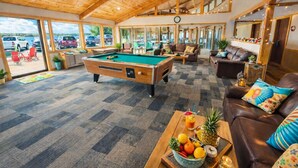 A pool table in a room with a checkered carpet, a billiards table, and a sofa with colorful cushions. - The Round Barn Lodge (Spring Green)