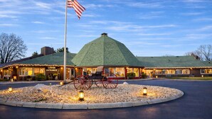 A lodge entrance with a green-roofed building, an American flag, and a horse-drawn carriage. - The Round Barn Lodge (Spring Green)