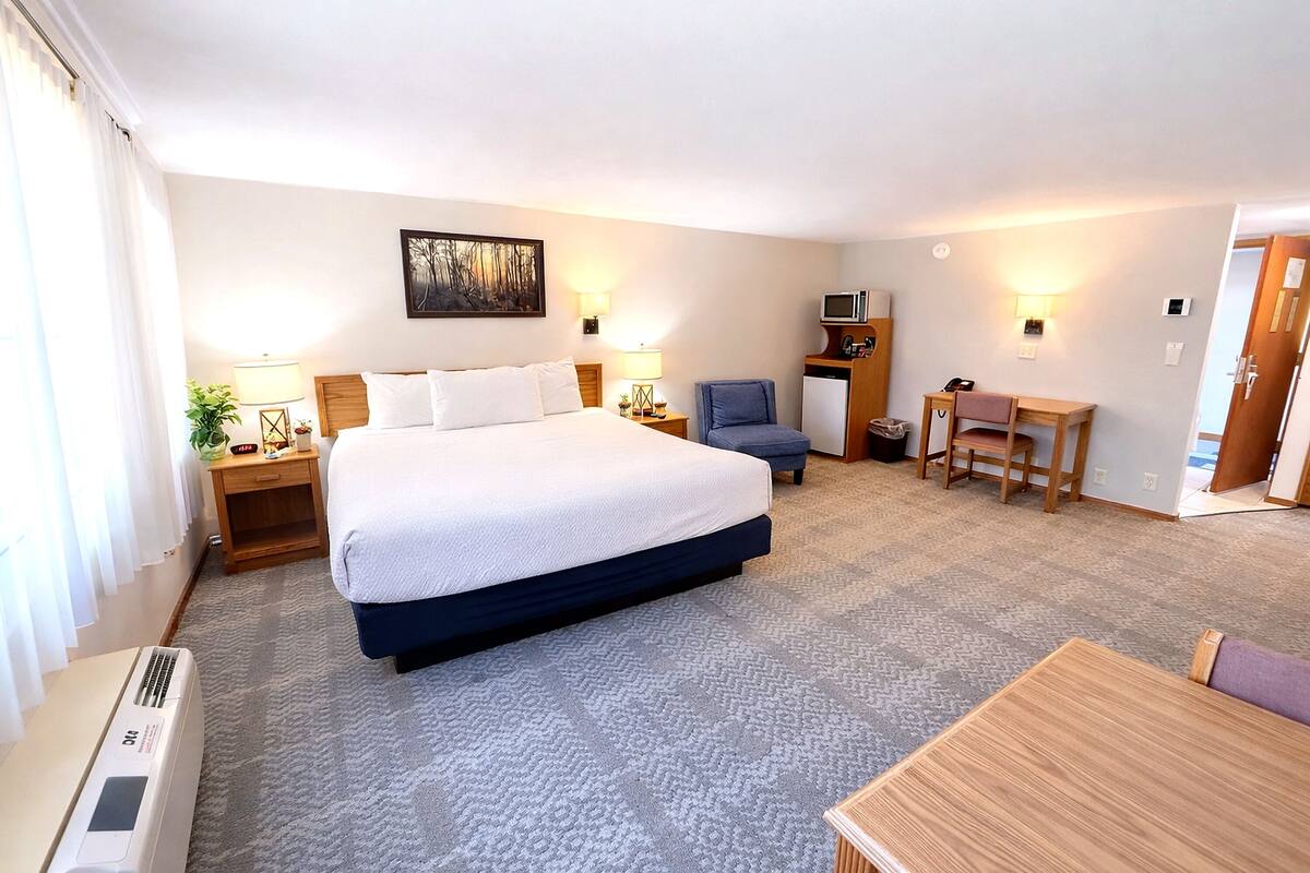 Une chambre d’hôtel avec un grand lit, un bureau, une chaise, une télévision et une lampe.