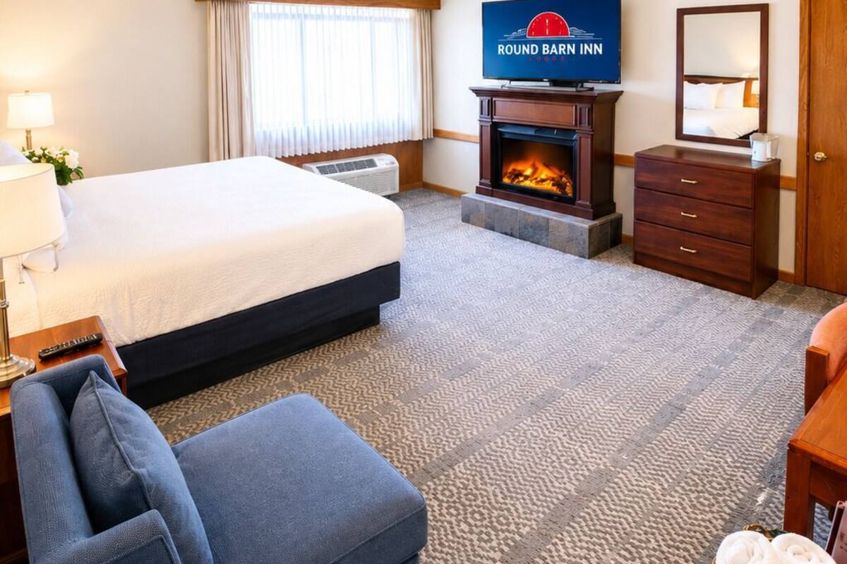 Une chambre d’hôtel équipée d’un lit, d’une télévision, d’une cheminée, d’un ventilateur de plafond, d’un bureau et d’une chaise.