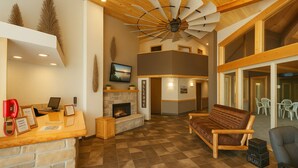 A reception area with a fireplace, a desk with a computer, a red telephone, and a sign with the hotel's name. - The Round Barn Lodge (Spring Green)