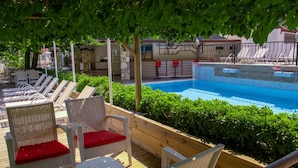 Un área junto a la piscina con sillones de descanso y una piscina pequeña.