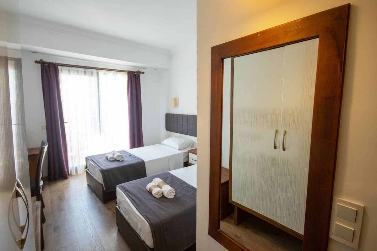 A hotel room with two beds, a large wardrobe, and a mirror.