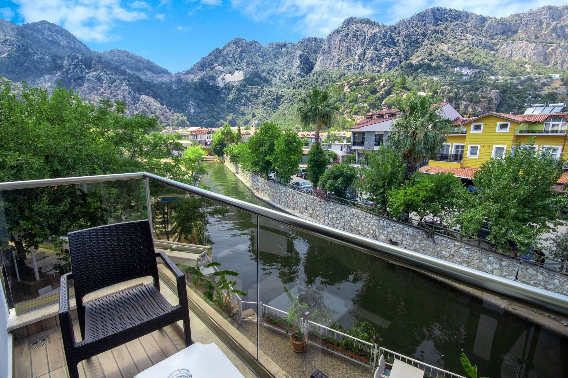 A balcony with a view of a river, mountains, and residential buildings.