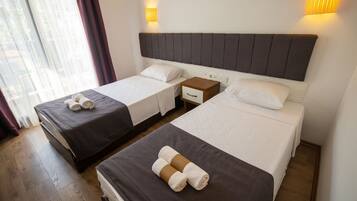 A hotel room with two beds, each with a wooden nightstand and a lamp.